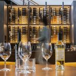 Wine is illuminated on a large win rack at the center of the main room at Long Shadows Woodinville Tasting Room & Key Club Lounge on Friday, Feb. 28, 2025 in Woodinville, Washington. (Olivia Vanni / The Herald)