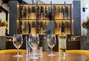 Wine is illuminated on a large win rack at the center of the main room at Long Shadows Woodinville Tasting Room & Key Club Lounge on Friday, Feb. 28, 2025 in Woodinville, Washington. (Olivia Vanni / The Herald)