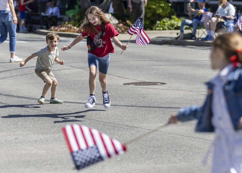 Benny Perkins, 5, and Eleanor Perkins, 8, run across Colby Avenue before the start of the Fourth of July parade on Friday, July 4, 2025 in Everett, Washington. (Olivia Vanni / The Herald)