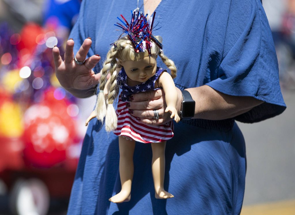 A person holds an American Girl Doll in an American flag dress during the Fourth of July parade on Friday, July 4, 2025 in Everett, Washington. (Olivia Vanni / The Herald)