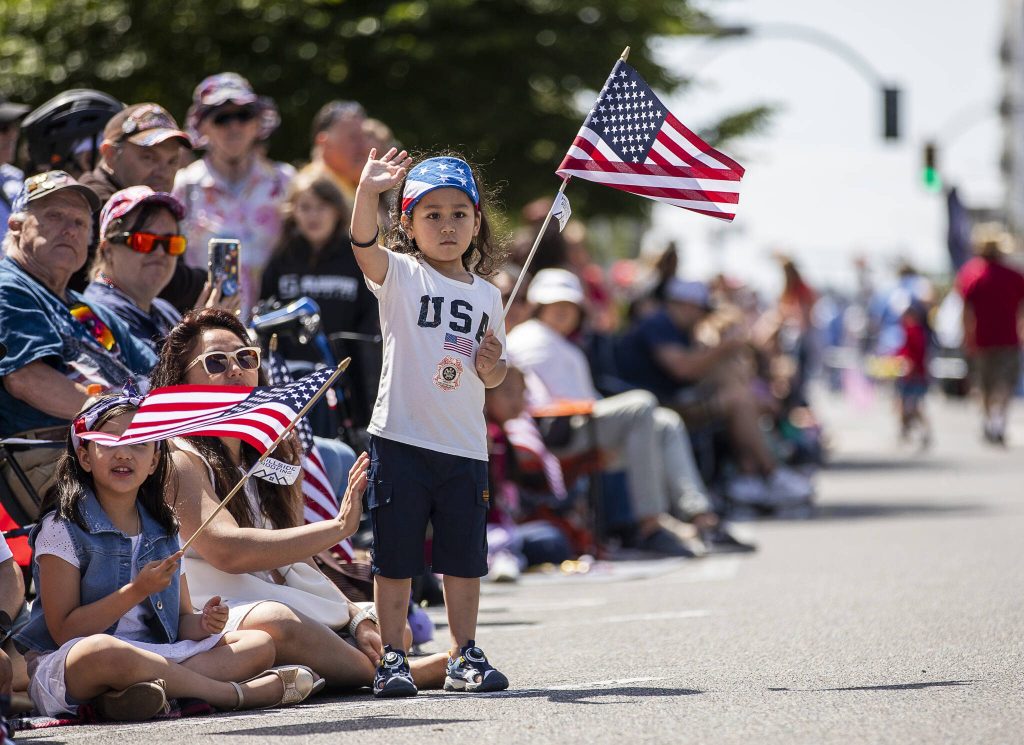 Liam Shakya, 3, waves at a float passing by during the Fourth of July parade on Friday in Everett. (Olivia Vanni / The Herald)