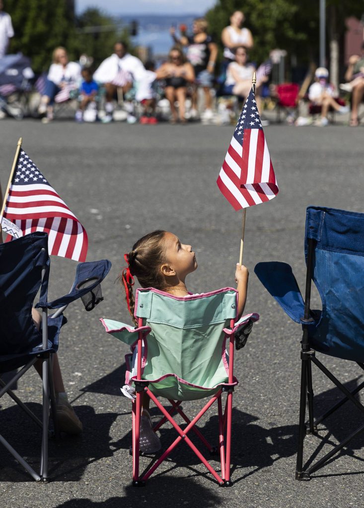 Campbell M., 4, looks up at her American flag during the Fourth of July Parade on Friday, July 4, 2025 in Everett, Washington. (Olivia Vanni / The Herald)