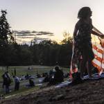 A child runs up a hill at Nile Shrine Golf Course wearing an American flag before the start of fireworks on Thursday, July 3, 2025 in Mountlake Terrace, Washington. (Olivia Vanni / The Herald)