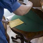 Annzolee Olsen shows the auction notes from her father with the poker table that was featured in a Robert Redford movie. (Olivia Vanni / The Herald)