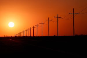 FILE — The sun sets over power lines in rural Ward County, Texas on Tuesday, May 20, 2025. Republicans plan to terminate billions of dollars in clean energy tax credits. Experts say that will mean more greenhouse gas emissions and more dangerous heat. (Paul Ratje/The New York Times)