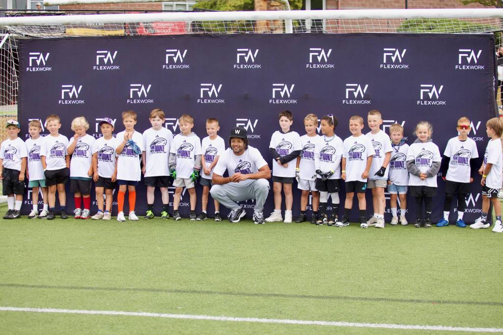 Rome Odunze poses for a photo with a group of kids at his youth football camp at Archbishop Murphy High School on July 10, 2025. (Joe Pohoryles / The Herald)