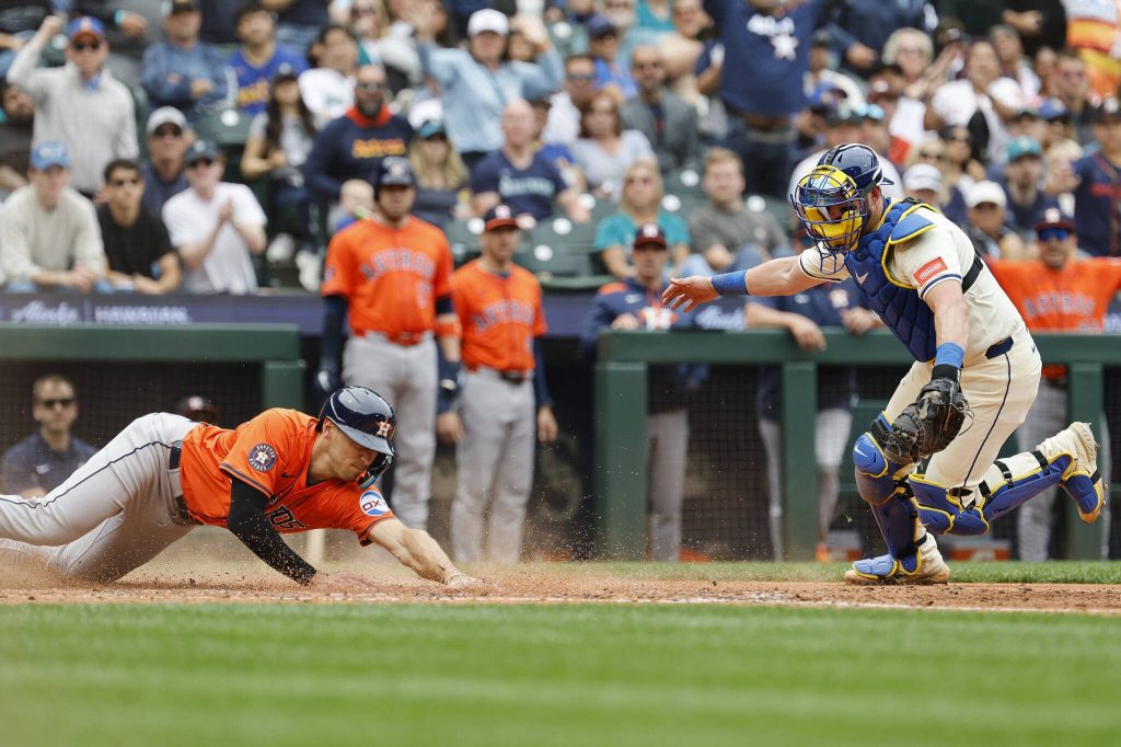 Shay Whitcomb (10) of the Houston Astros looks to avoid Mitch Garver (18) of the Seattle Mariners tag at home plate to score off of Cam Smiths two-run RBI double during the fifth inning against the Seattle Mariners at T-Mobile Park on Sunday in Seattle. (Alika Jenner / Getty Images / Tribune News Services)