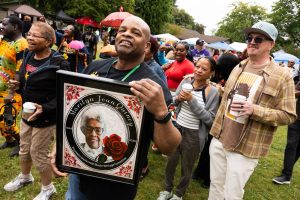 Tony Quincy, Marylin Quincy's son, holds up a portrait honoring her during a second line parade at the 33rd annual Nubian Jam on Saturday, July 26, 2025, at Forest Park in Everett, Washington. (Will Geschke / The Herald)