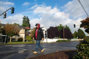 A rainbow stretches across the sky as a man walks to the school bus stop to pick up his child during a brief moment of rain in 2022 near Hall Park on Casino Road in Everett. (Ryan Berry / The Herald)