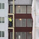 A man works on a balcony at the Cedar Pointe Apartments, a 255-apartment complex for senior 55+, at 17309 40th Avenue in 2020 in Arlington. In June, Washington attorney general Nick Brown named the owners of the Cedar Pointe complex as one of five defendants in a complaint alleging they engaged in unfair and deceptive practices. (Andy Bronson / The Herald)