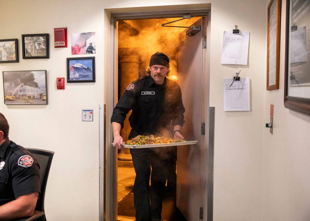 Ryan Fromm walks into the Everett fire station with a steaming tray of chicken and vegetables for dinner. (Olivia Vanni / The Herald)
Ryan Fromm walks into the Everett fire station with a steaming tray of chicken and vegetables for dinner. (Olivia Vanni / The Herald)