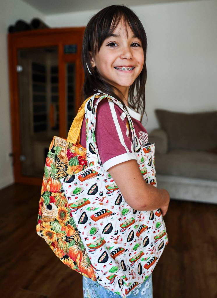 Eisley Lewis, 9, shows two examples of tote bags she made on Wednesday, Aug. 27, 2025 in Everett, Washington. (Olivia Vanni / The Herald)