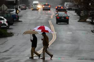 Pedestrians using umbrellas, some Washingtonians use them, as they cross Colby Avenue under pouring rain on Tuesday, Nov. 28, 2017 in Everett, Wa. The forecast through Saturday is cloudy with rain through Saturday. (Andy Bronson / The Herald)