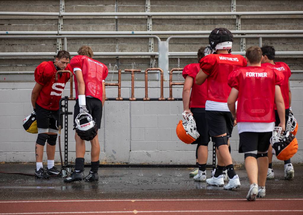 Players pause to get water between drills during football practice at Snohomish High School on Thursday, Aug. 28, 2025 in Snohomish, Washington. (Olivia Vanni / The Herald)