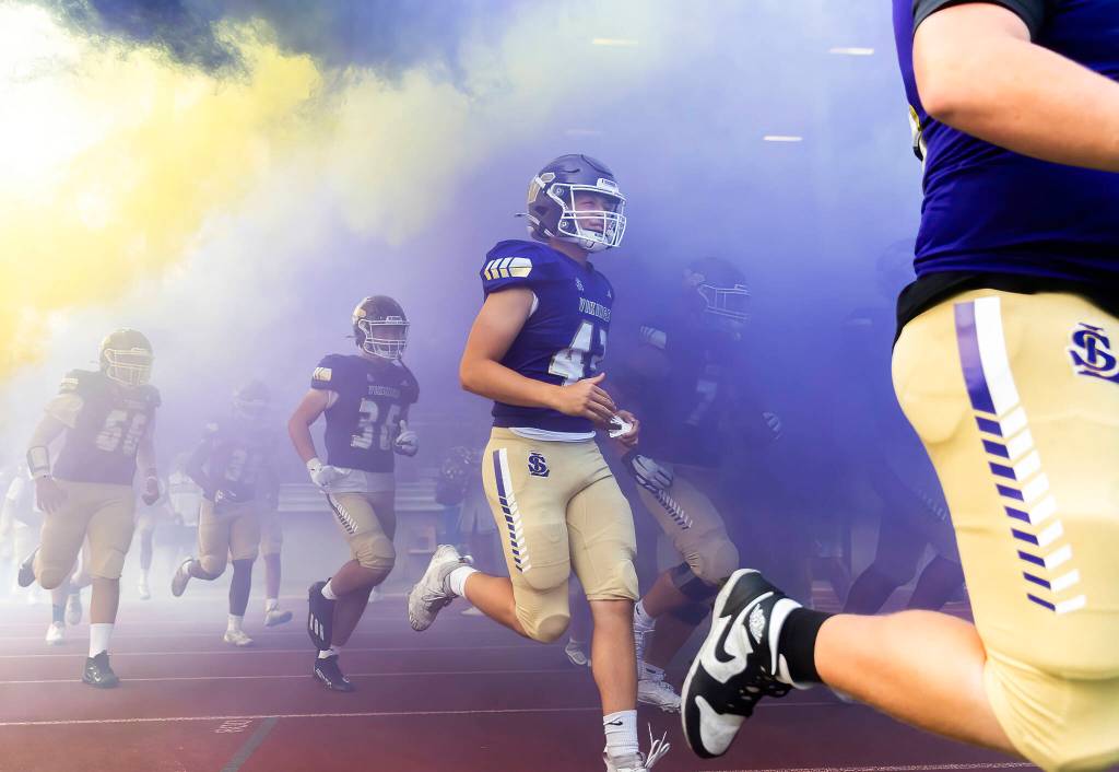 Lake Stevens players run through colored smoke onto the field before the game against Sumner on Friday, Sept. 5, 2025 in Lake Stevens, Washington. (Olivia Vanni / The Herald)