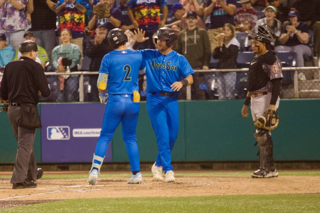 AquaSox catcher Matthew Ellis (right) greets third baseman Luis Suisbel at home plate following the latters go-ahead, two-run home run to help Everett beat the Eugene Emeralds 6-3 in Game 4 to clinch the 2025 Northwest League Championship at Funko Field on Sept. 13, 2025. (Joe Pohoryles / The Herald)