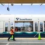 Two workers walk past a train following a press event at the Lynnwood City Center Link Station on Friday, June 7, 2024, in Lynnwood, Washington. Sound Transit is weighing proposed cost savings to counter rising costs for the Everett Link extension. (Ryan Berry / The Herald)