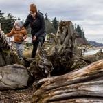 Boone Bisbey, 2, and Hunnika Bisbey, 39, walk along the beach and driftwood at Lighthouse Park in Mukilteo, Washington, on Wednesday, Jan. 3, 2024. (Annie Barker / The Herald)