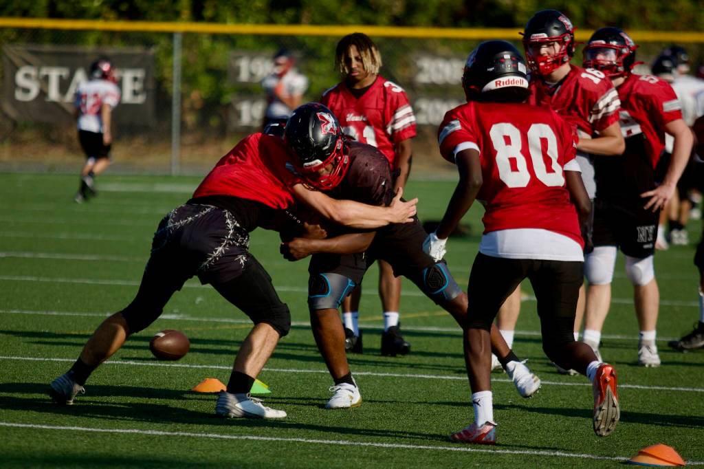Mason Wilson (center in black) makes contact in a drill while carrying the ball during practice at Mountlake Terrace High School on Sept. 23, 2025. (Joe Pohoryles / The Herald)