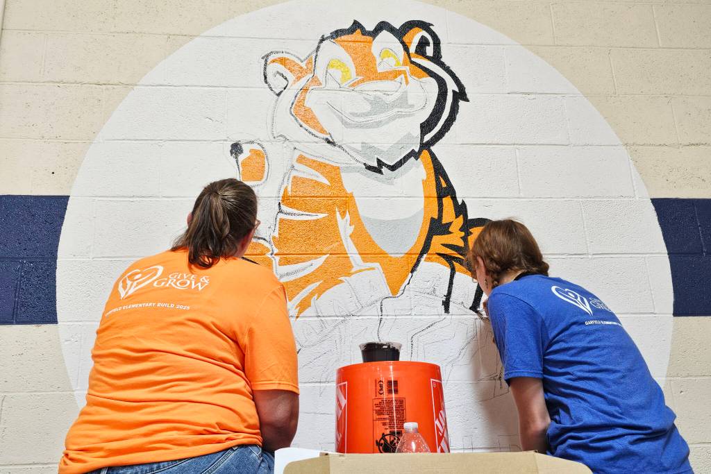 Provided photos
Two of more than 90 volunteers paint the school mascot at Garfield Elementary School on Sept. 12 in Everett.