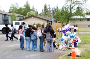 Students from Explorer Middle School gather Wednesday, May 7, 2025, at the site where Emiliano Emi Munoz died May 5 in an electric bicycle accident in south Everett, Washington. The makeshift memorial included lit candles, flowers, balloons, posters made by students and chalk messages on the pavement. (Aspen Anderson / The Herald)