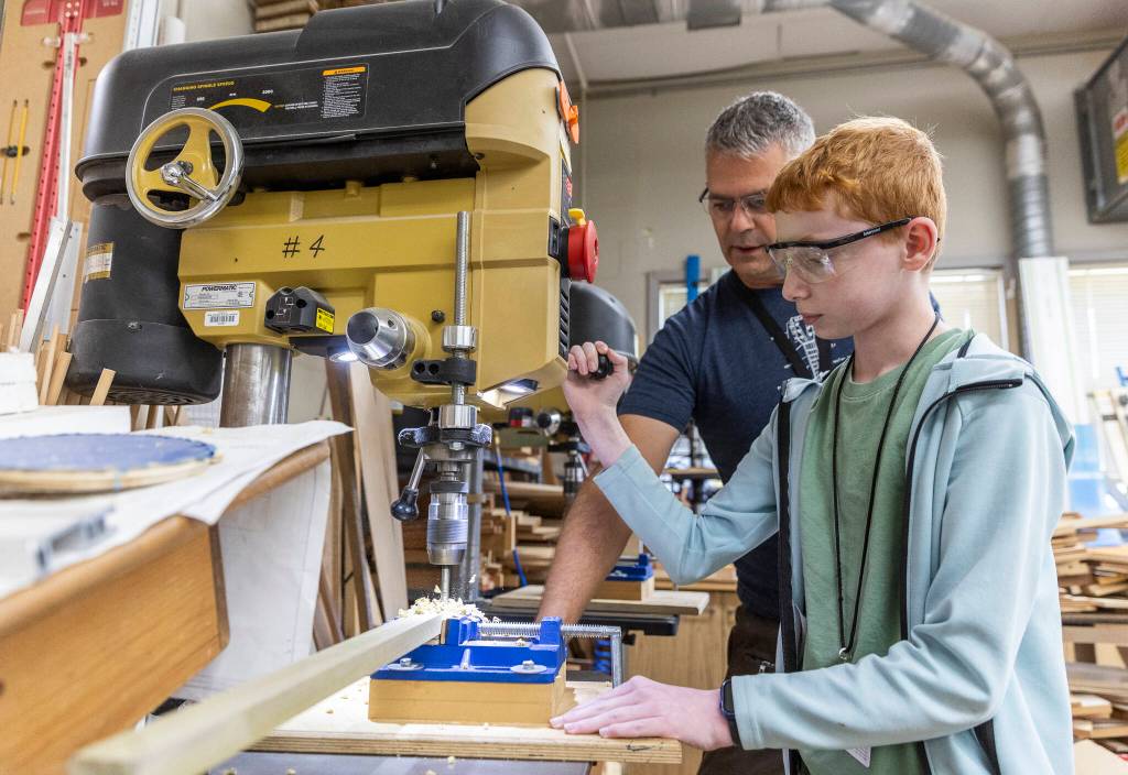 Adam Allen, 12, drills a hole in the neck of his canjo with the help of teacher Alex Moll during class on Oct. 7, 2025 in Lake Stevens, Washington. (Olivia Vanni / The Herald)