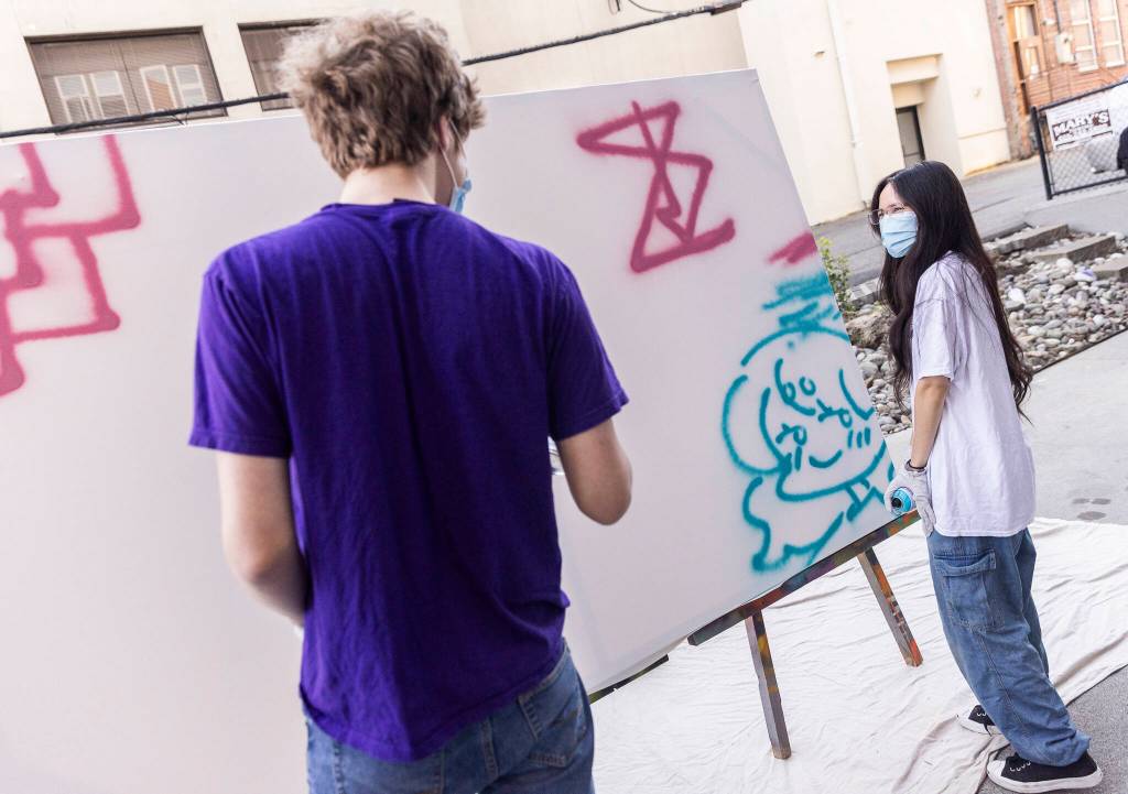 Sarah White spray paints a figure on a canvas during Teen Night at the Schack Art Center on Sept. 18, 2025 in Everett, Washington. (Olivia Vanni / The Herald)