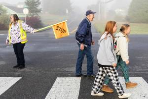 Grandpa Buzz smiles while he crosses the street and greets people along the way as he walks to Cascade View Elementary on Sept. 30, 2025 in Snohomish, Washington. (Olivia Vanni / The Herald)