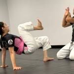 Lynnwood Officer Maryam McDonald demonstrates a guard get-up with Bellevue Officer Craig Hanaumi at PandaRoll JiuJitsu on Oct. 4 in Lynnwood. (Jenna Millikan / The Herald)