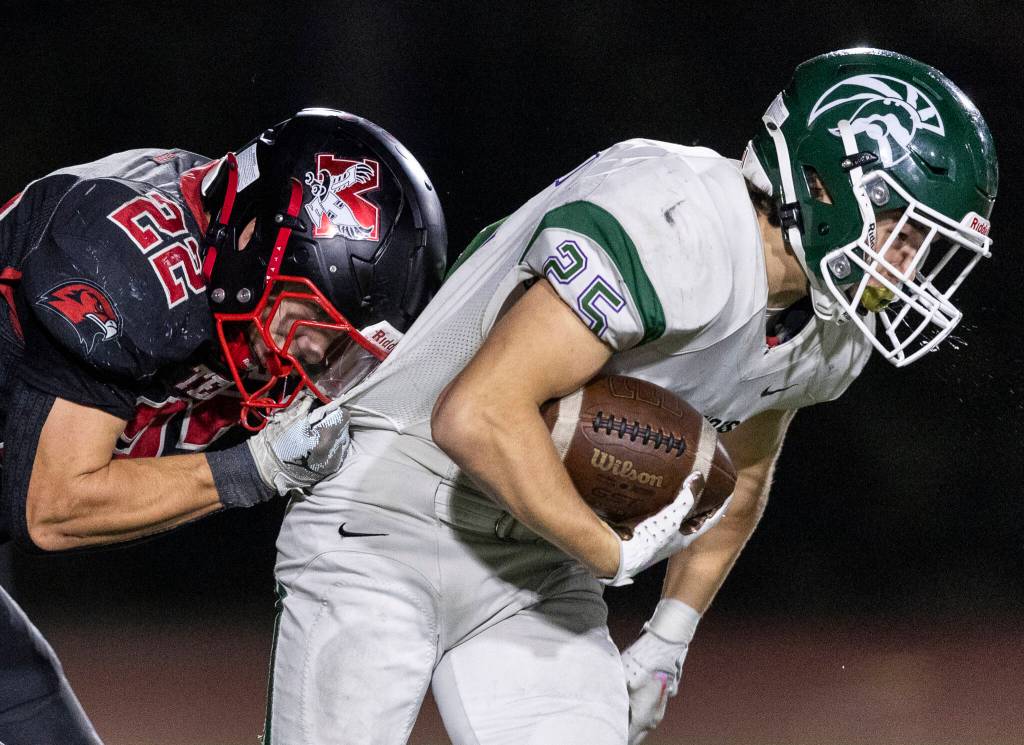 Edmonds-Woodways Gaige Lynch spits while he is tackled by Mountlake Terraces Owen Boswell during the game on Oct. 23, 2025 in Edmonds, Washington. (Olivia Vanni / The Herald)