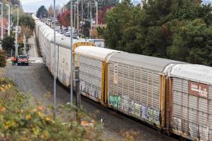 A train sits on the tracks while BNSF workers stand next to the site of a car and train collision at the intersection of Railroad Avenue and Main Street on Oct. 28, 2025 in Edmonds, Washington. (Olivia Vanni / The Herald)