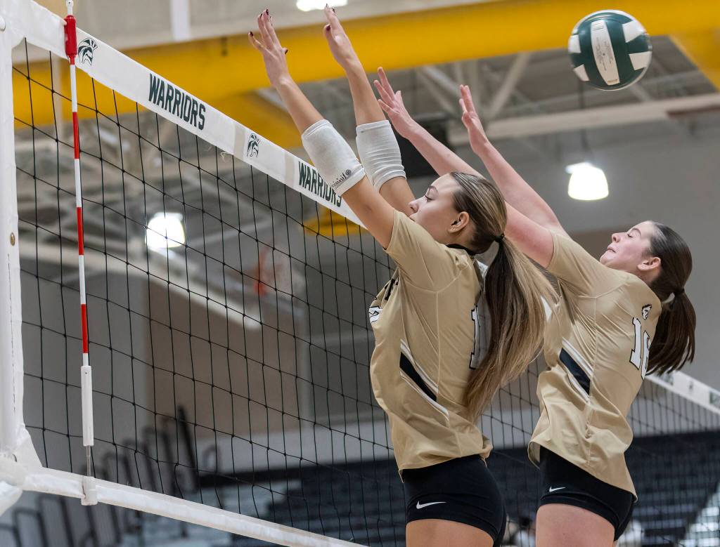 Lynnwoods Evelyn Hall and Audrey Williams jump to block the ball during the game against Edmonds-Woodway on Oct. 29, 2025 in Edmonds, Washington. (Olivia Vanni / The Herald)