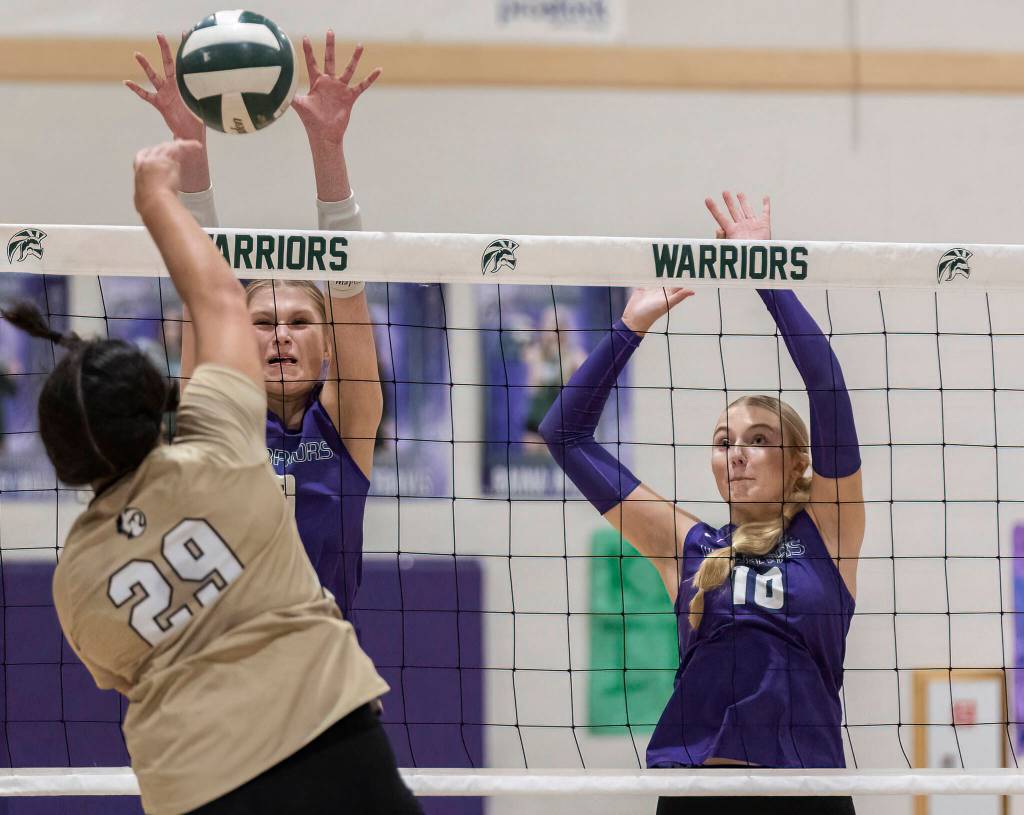 Lynnwoods Makena Kaleo spikes the ball over the net while Edmonds-Woodways Eva Belova and Raina Wilson jump up to block during the game on Oct. 29, 2025 in Edmonds, Washington. (Olivia Vanni / The Herald)