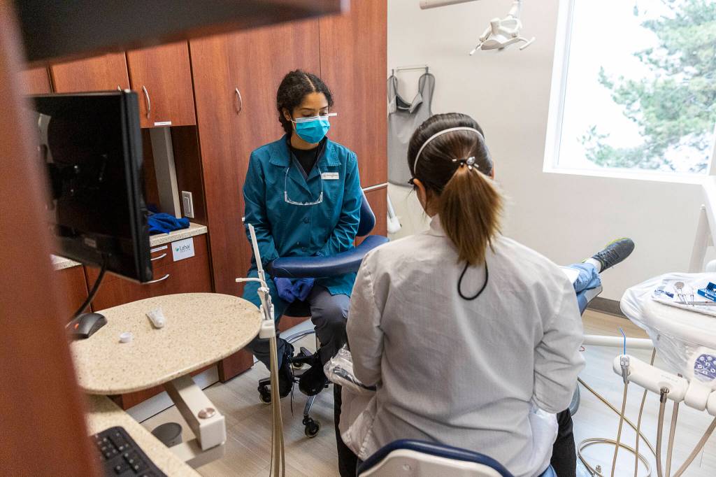 Dental Assistant Dominique Robertson works with a patient on Oct. 28 in Lynnwood. (Olivia Vanni / The Herald)
