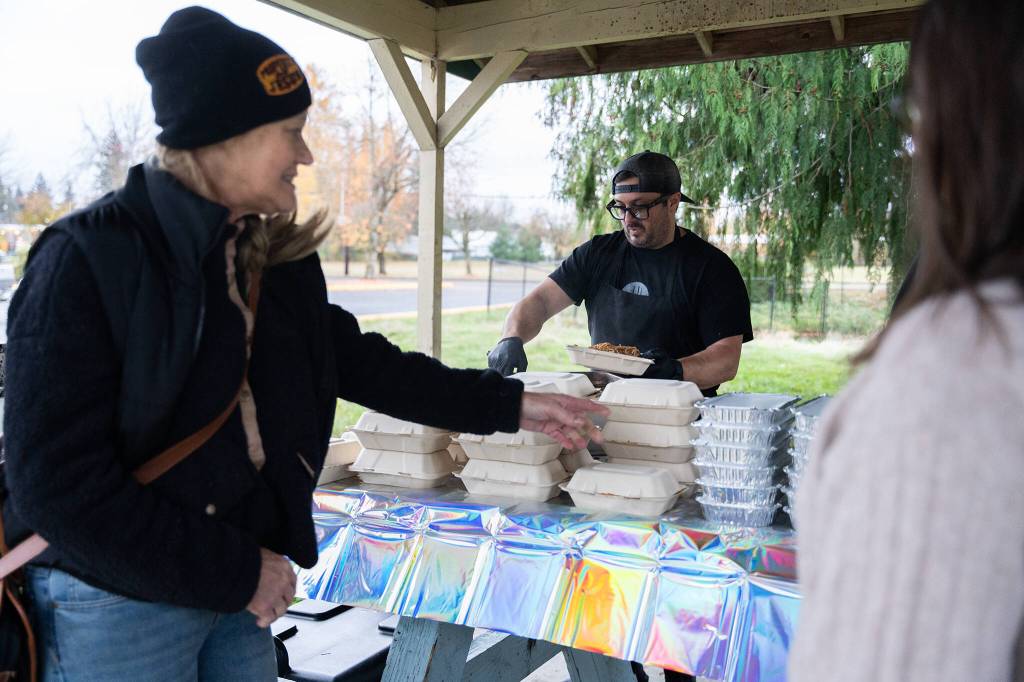photos by Will Geschke / The Herald 
Alex Petrakopolos, center, helps distribute warm food to community members on Monday in Granite Falls.
