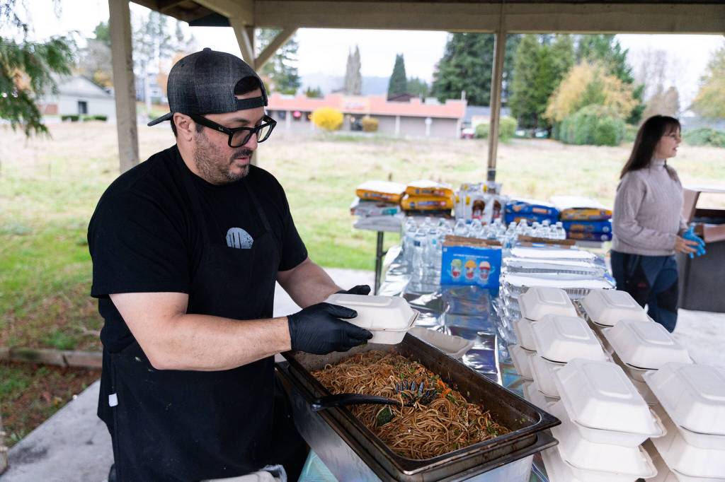 Alex Petrakopolos helps distribute warm food to community members on Monday in Granite Falls. (Will Geschke / The Herald)