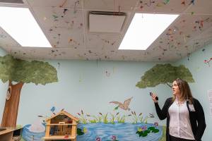 Gretchen Clark Bower explains that each sticky hand hanging from the ceiling was stuck there by a child that came through the exam room at the Providence Intervention Center on Nov. 21, 2025 in Everett, Washington. (Olivia Vanni / The Herald)