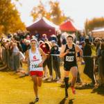 Arlington junior Ramon Little (right) runs alongside Stanwoods Max Grennell during the WIAA Cross Country State Championships at Sun Willows Golf Course in Pasco on Nov. 8, 2025. Little won the ambulatory championship in 12:29.2 on the 2.1-mile course, while Grennell competed as a partner in the unified race, which happened concurrently with the ambulatory race. (Photo courtesy Krissy Kolbeck / Arlington Cross Country / WIAA).