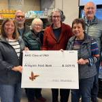 Arlington Community Food Bank Executive Director Carla Rankin, left, stands holding an oversized check with Krista Galde, right, along other members of the Arlington High School class of 1965. Members of the class decided to donate money saved for their next class reunion to the food bank instead. (Taylor Scott Richmond / The Daily Herald)