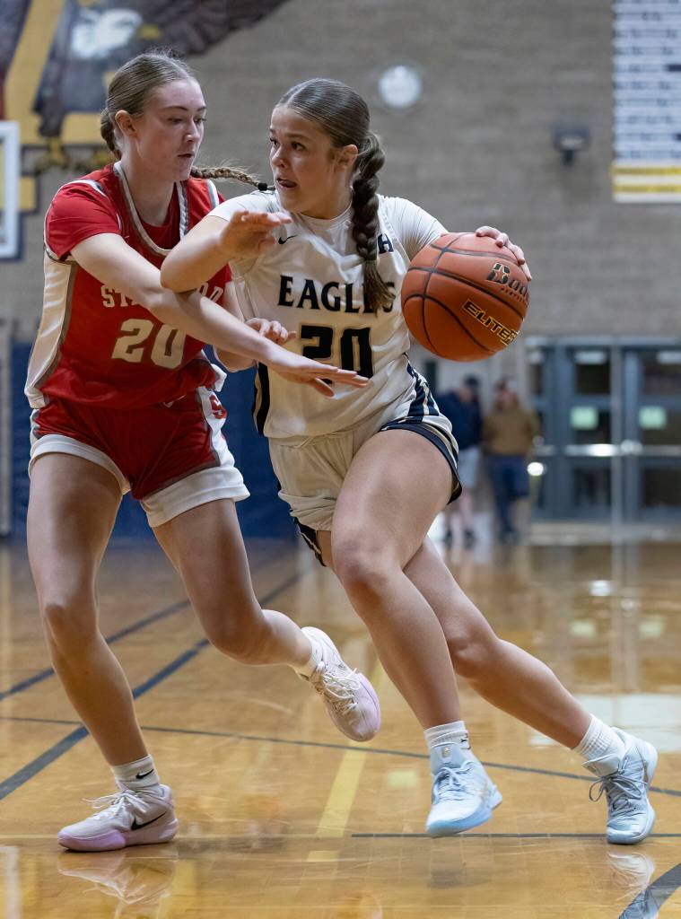 Arlingtons Finley Walker drives to the hoop while being guarded by Stanwoods Presley Harris during the game on Dec. 3, 2025 in Arlington, Washington. (Olivia Vanni / The Herald)