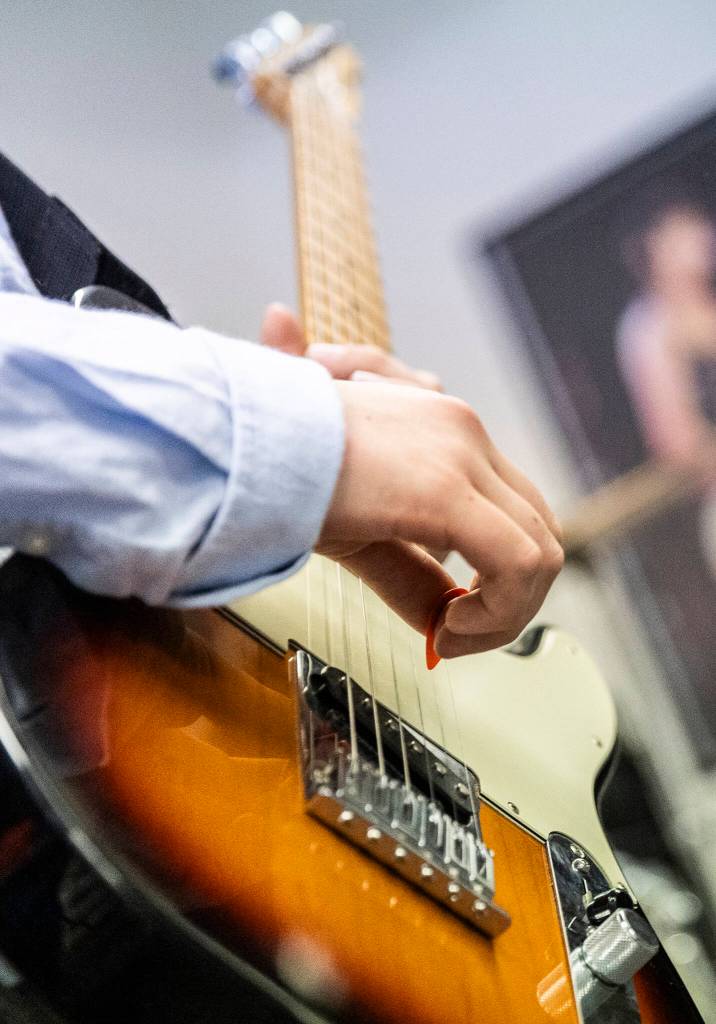 A student uses a pick while playing at The Music Circle on Dec. 1, 2025, in Everett, Washington. (Olivia Vanni / The Herald)