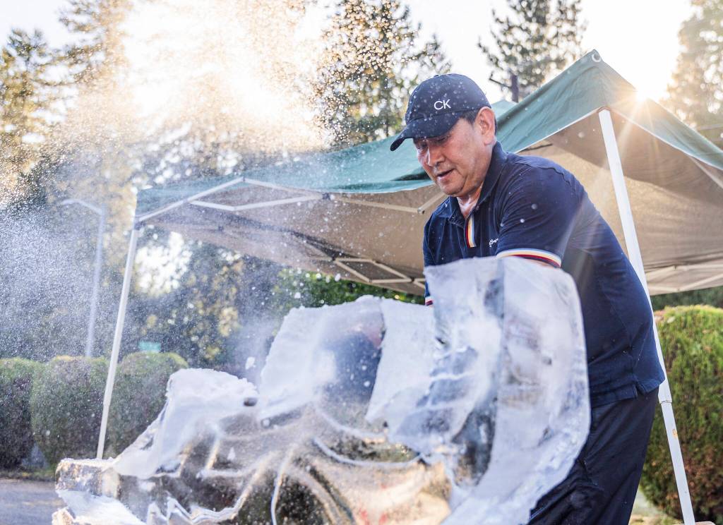 Ice and water spray as Chan Kitburi begins to carve out pieces of ice on his sculpture outside of his home on Sept. 17, 2025 in Marysville, Washington. (Olivia Vanni / The Herald)