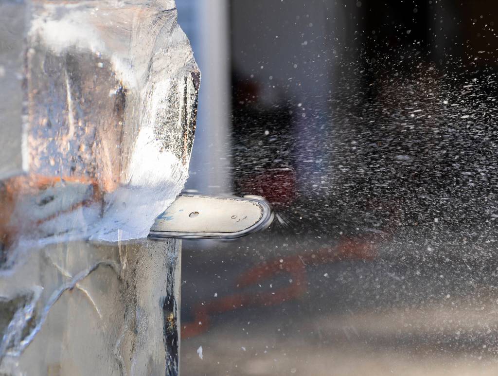 A chain saw sprays ice and water as Kitburi carves large ice chunks out of his sculpture on Sept. 17, 2025 in Marysville, Washington. (Olivia Vanni / The Herald)