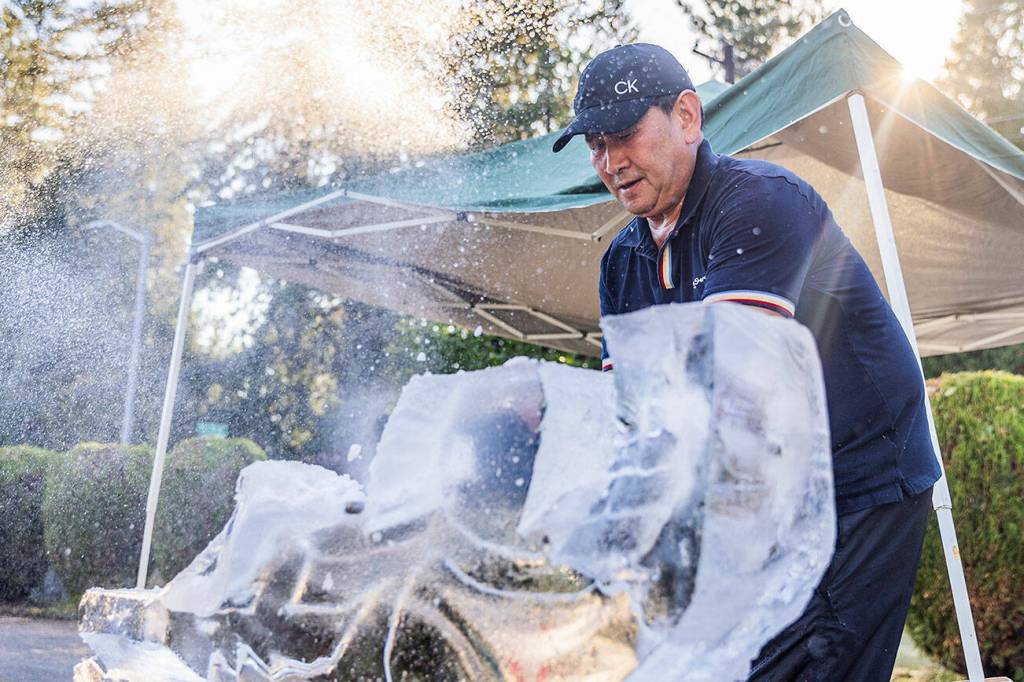 Ice and water spray as Chan Kitburi begins to carve out pieces of ice on his sculpture outside of his home on Sept. 17, 2025 in Marysville, Washington. (Olivia Vanni / The Herald)