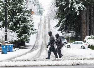 Pedestrians try to navigate the snow and slush covering the roads and sidewalks along 100th Avenue West on Thursday, Feb. 6, 2025 in Edmonds, Washington. (Olivia Vanni / The Herald)