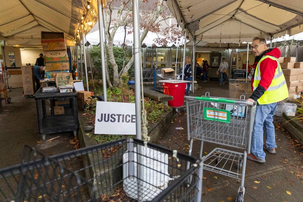 Volunteers bring carts back inside after food is delivered to customers cars at the Edmonds Food Bank on Dec. 8, 2025, in Edmonds, Washington. (Olivia Vanni / The Herald)