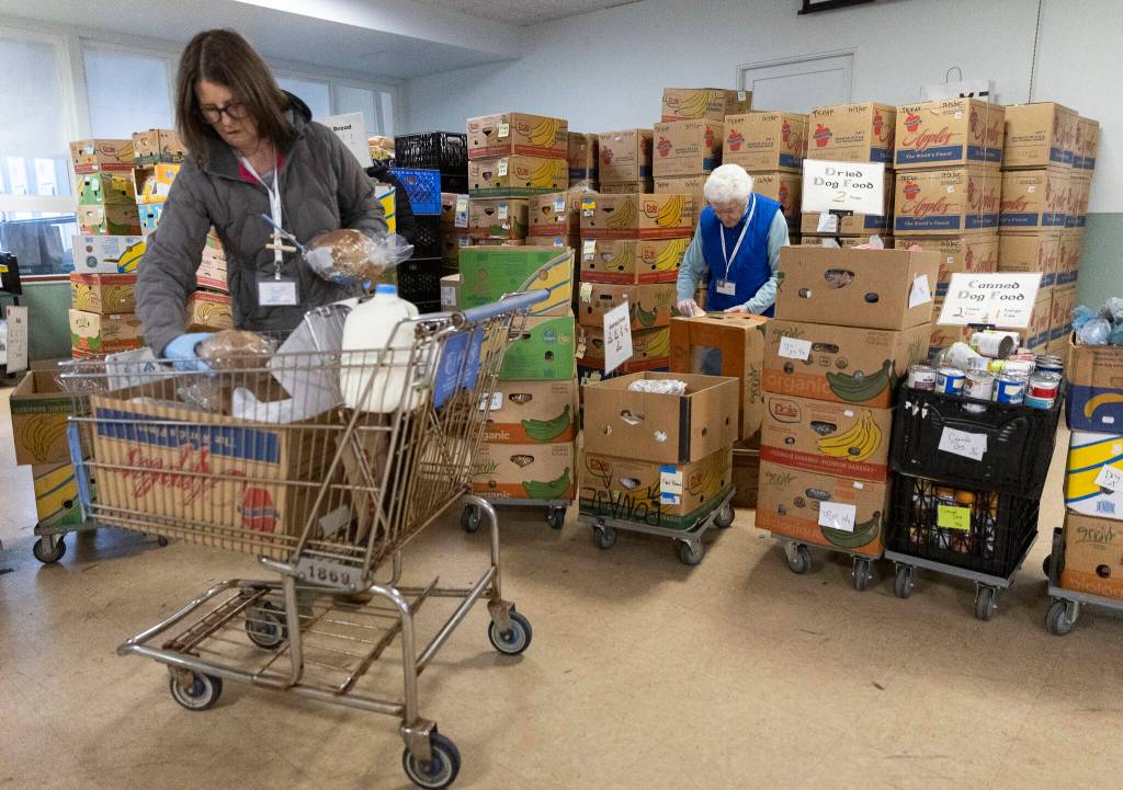 Volunteers Erin Keeton, left, and Judy OMalley, right, put together a customers order at the Edmonds Food Bank on Dec. 8, 2025, in Edmonds, Washington. (Olivia Vanni / The Herald)