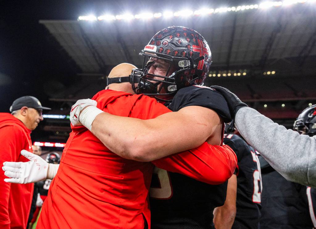 Archbishop Murphys Jack Sievers hugs his coach after winning the 2A state championship game against Tumwater at Husky Stadium on Saturday, Dec. 6, 2025 in Seattle, Washington. (Olivia Vanni / The Herald)