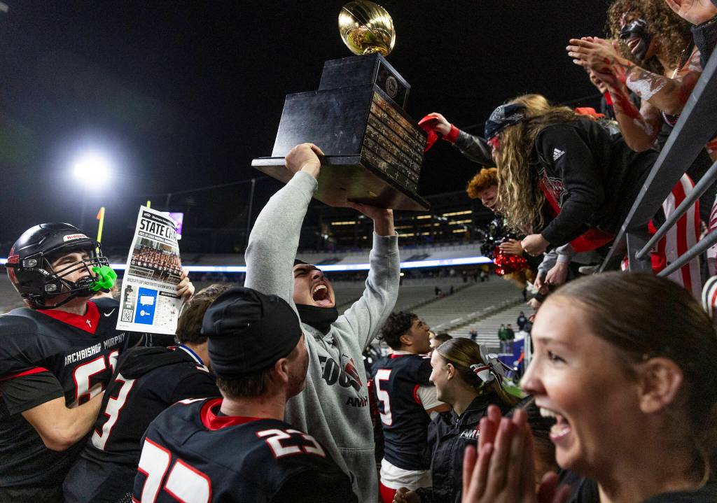 Archbishop Murphys Tayden Olson holds up the 2A state championship trophy to the Archbishop Murphy student section at Husky Stadium on Saturday, Dec. 6, 2025 in Seattle, Washington. (Olivia Vanni / The Herald)