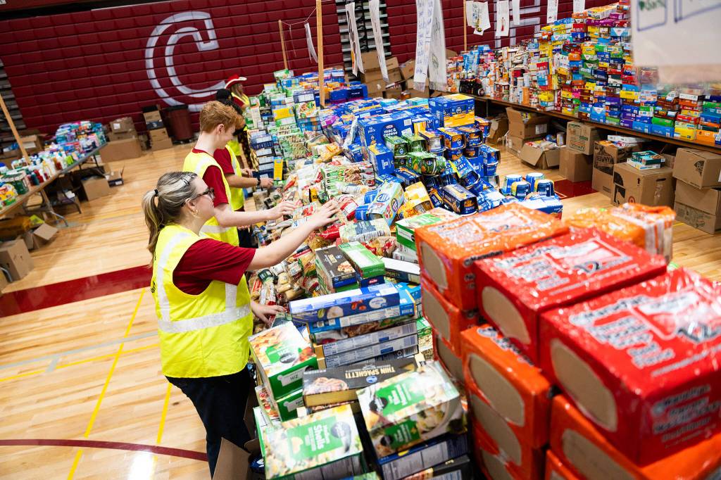 Finley Mikesell, 17, front, works with students to organize food in Cascade High School during its annual food drive event on Wednesday, Dec. 17, 2025, in Everett, Washington. (Will Geschke / The Herald)